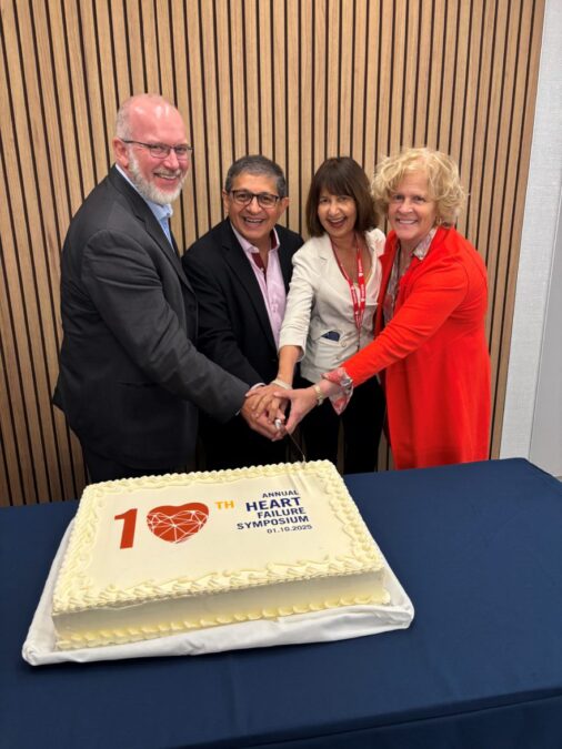 Four executive members of the Ted Rogers Centre for Heart Research gather around for a celebratory cake cutting